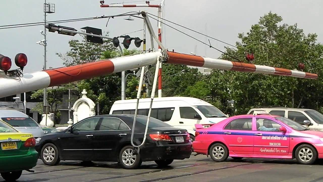 Cars crossing a level crossing with barriers in Bangkok.