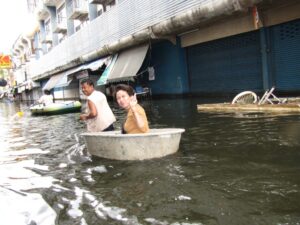 Couple carrying a basin in a flooded road in Thailand.