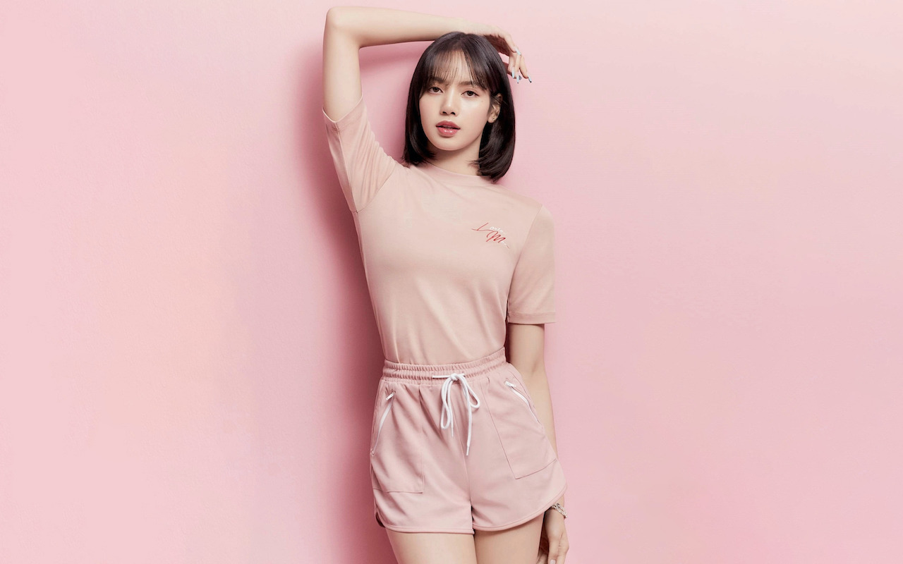 Lisa Manoban of BLACKPINK posing on a pink background.