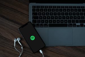 A mobile phone with the Spotify logo, near a MacBook Pro.