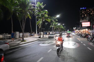 Motorcycle taxi driver on a motorcycle on a Pattaya street at night.