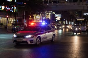A police car driving by Terminal 21 in Bangkok at night.