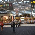 Inside the departures terminal at Suvarnabhumi International Airport in Bangkok. Gates and VAT Refund signs and the statue of the Hindu gods known as "stirring the ocean"