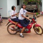 Young schoolgirls driving a motorcycle in Thailand
